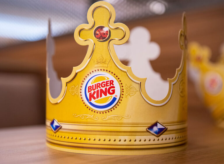 The image is of Burger king crown on the table. On the crown there is burger king logo written as burger king