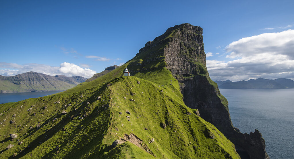 The image is of Kallur Lighthouse, which is located on Kalsoy Island in the Faroe Islands Denmark. The Faroe Islands are a group of volcanic islands in the North Atlantic Ocean.