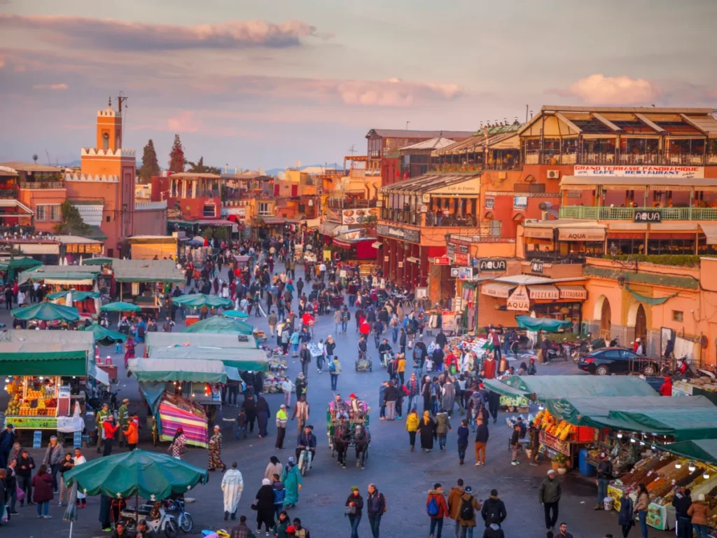 This image is of Marrakech Morocco the top place to travel where people is walking the sun is about to set. 