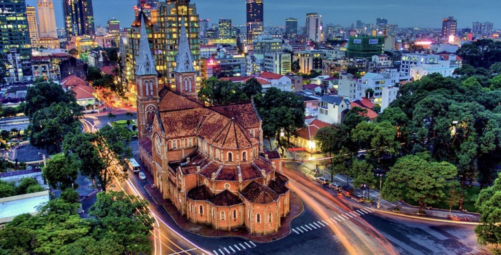 A photo of Notre Dame Cathedral Basilica of Saigon, a large cathedral with two bell towers, illuminated at night. The text "UU REL" is written on the building.