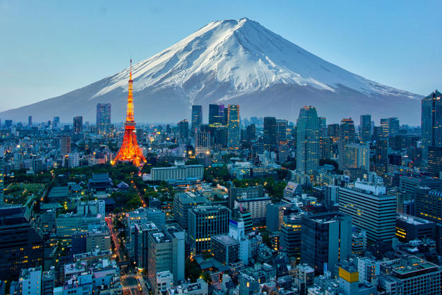 Tokyo japan city skyline with a mountain in the background. The most prominent building is a skyscraper in the center of the image.