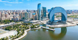 The images shows Everyone Going To Azerbaijan. In this picture there is a beautiful view of it. there is a lake and surrounded by the buildings.