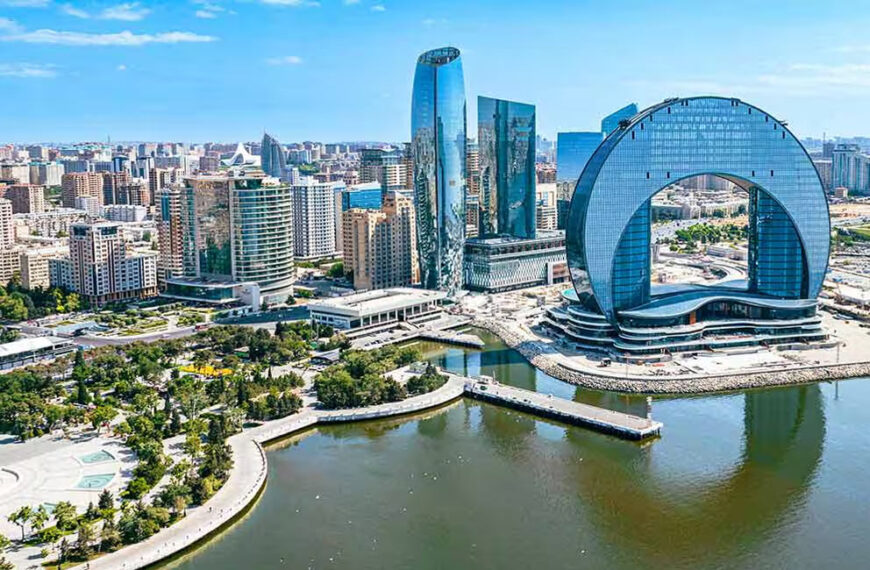 The images shows Everyone Going To Azerbaijan. In this picture there is a beautiful view of it. there is a lake and surrounded by the buildings.