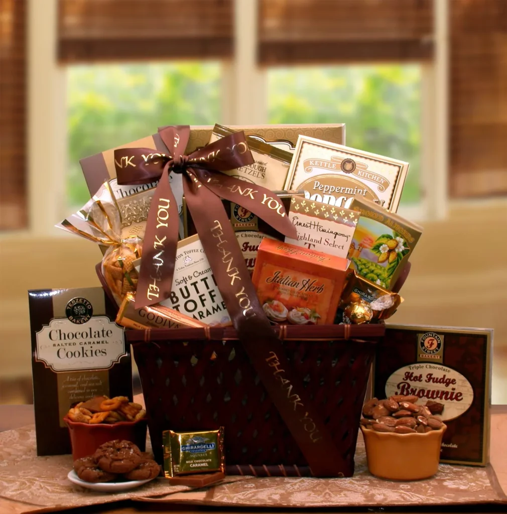 A gourmet gift basket filled with various chocolate treats, including cookies, truffles, and brownies. There are also other items like coffee, tea, and nuts. The basket is tied with a ribbon and includes several "Thank You" messages.