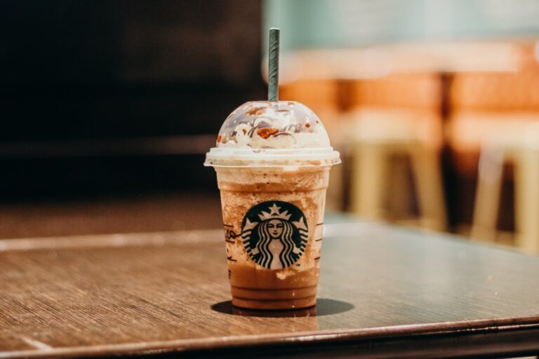 A close-up of a Starbucks iced coffee drink with whipped cream and chocolate drizzle, showcasing the process behind crafting this popular beverage.