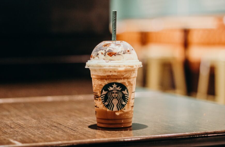 A close-up of a Starbucks iced coffee drink with whipped cream and chocolate drizzle, showcasing the process behind crafting this popular beverage.